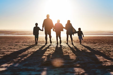 family walking on beach at sunset