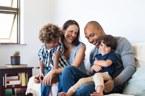 Family with dad, mom, and two young kids sitting on their couch